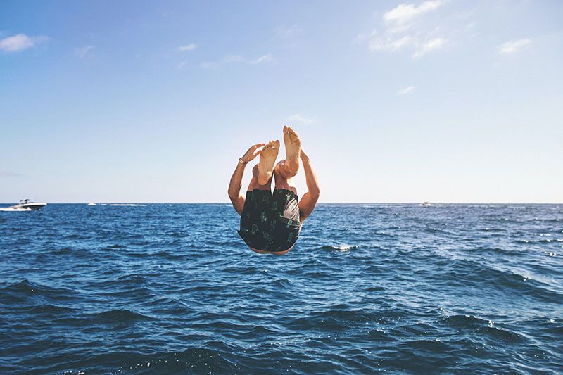 La vue arrière d'un homme qui plonge dans l'eau.