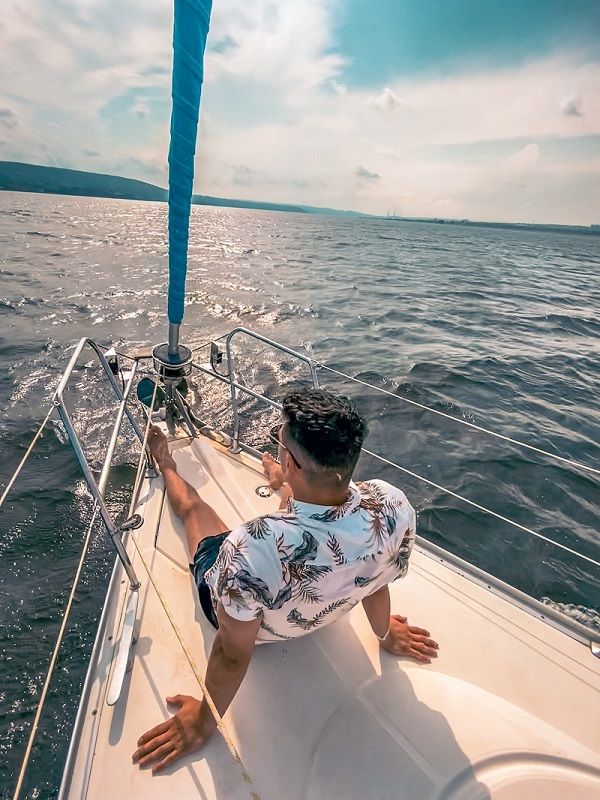 Un jeune homme à bord d'un bateau regarde la mer.
