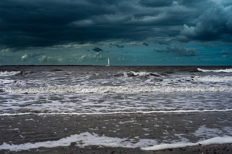 Voilier au loin avec des nuages d'orage menaçants