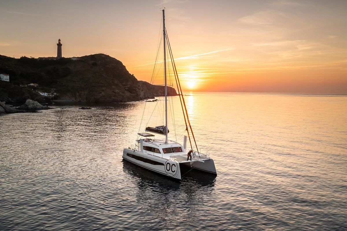 Un catamaran à moteur dans une baie tranquille au coucher du soleil