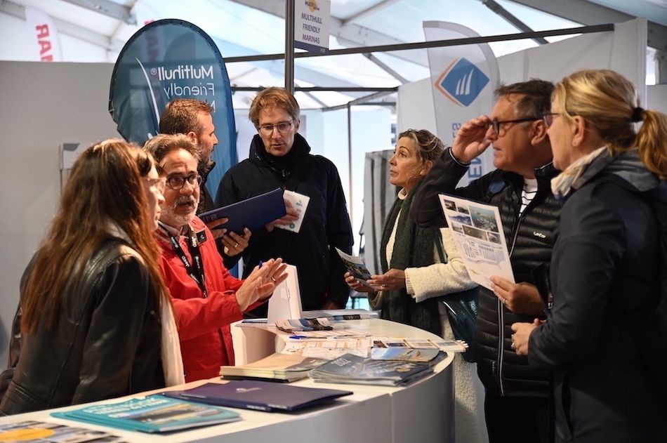 Des visiteurs discutent avec des vendeurs dans le village des exposants du salon international du multicoque.