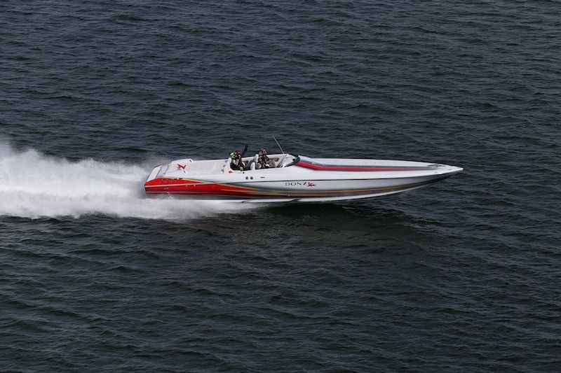 Un hors-bord rouge et blanc filant à toute allure sur l'eau sombre. 