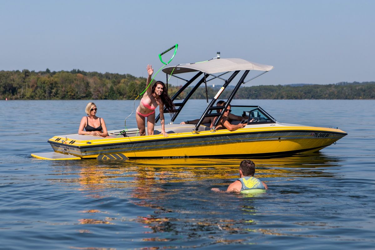 une femme lance une corde de remorquage à un wakeboarder