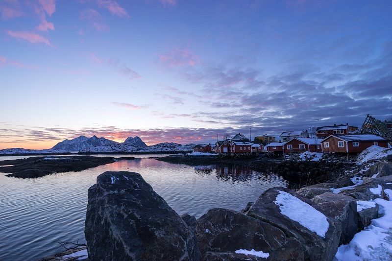 Un lever de soleil d'hiver dans un village de pêcheurs tranquille avec les montagnes en arrière-plan.