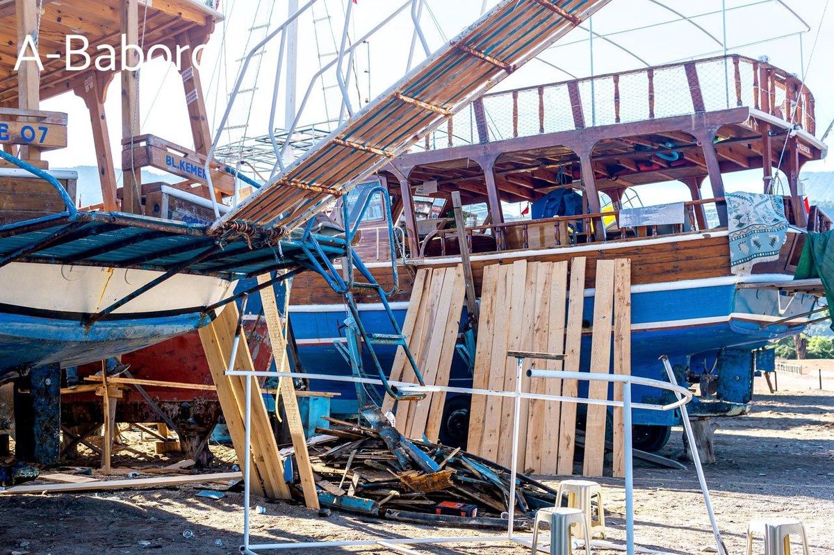 Atelier de réparation de bateau en plein air sur la côte de Cirali, essentiel pour l'autonomie en mer.