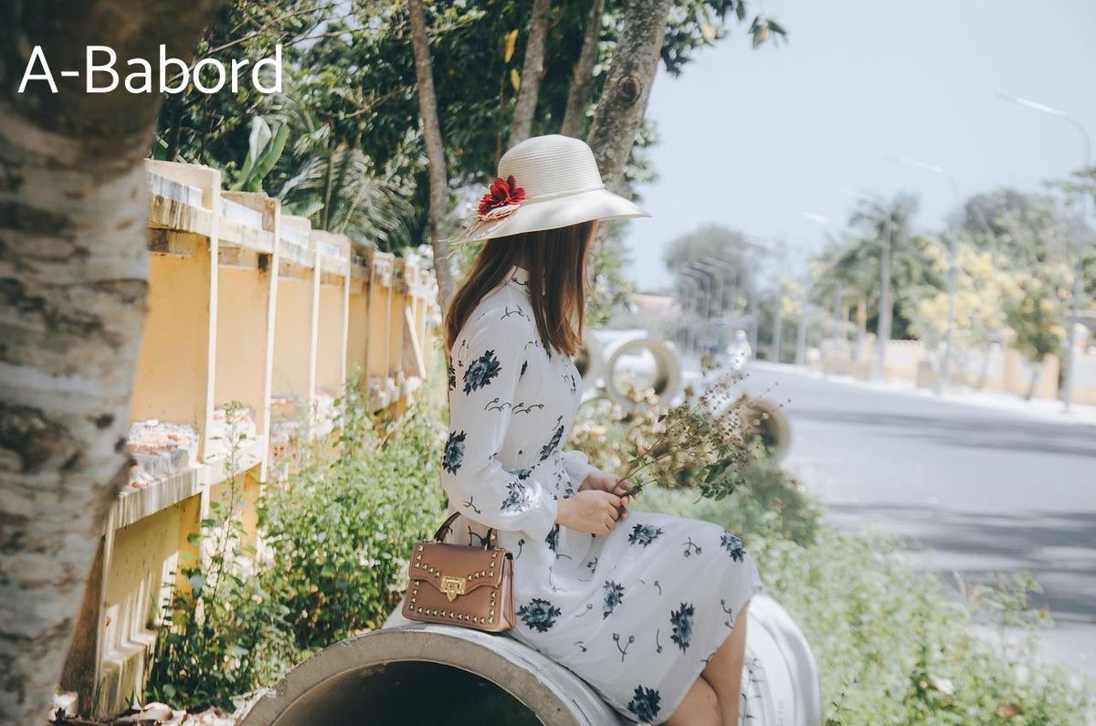 Élégance estivale : robe à motifs et chapeau en harmonie sous le ciel ensoleillé.