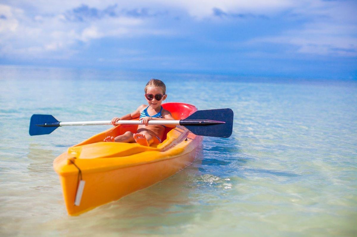 Enfants en kayak sur une eau calme, une activité nautique sécurisée adaptée aux jeunes débutants.