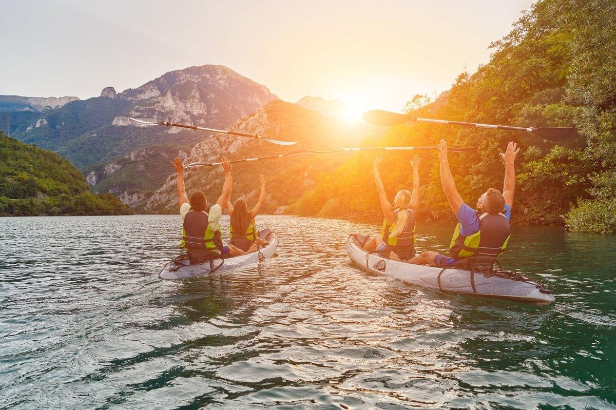 Famille pratiquant le paddle et le kayak sur un lac paisible lors d'une journée ensoleillée, idéale pour des activités nautiques.