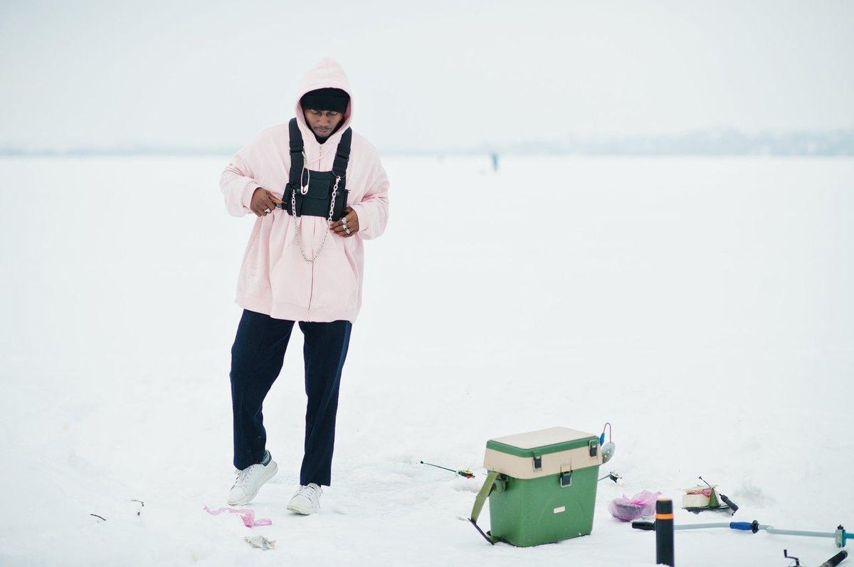 Fisher en waders néoprène hiver, équipé pour la pêche en eau froide avec parapluie et accessoires.