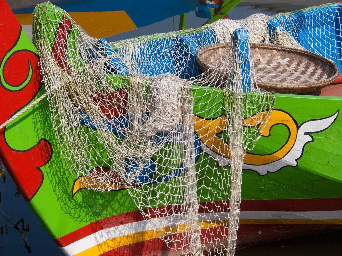 Fisherman wearing technical gear on a boat in rough sea, ensuring safety and comfort during deep-sea fishing.