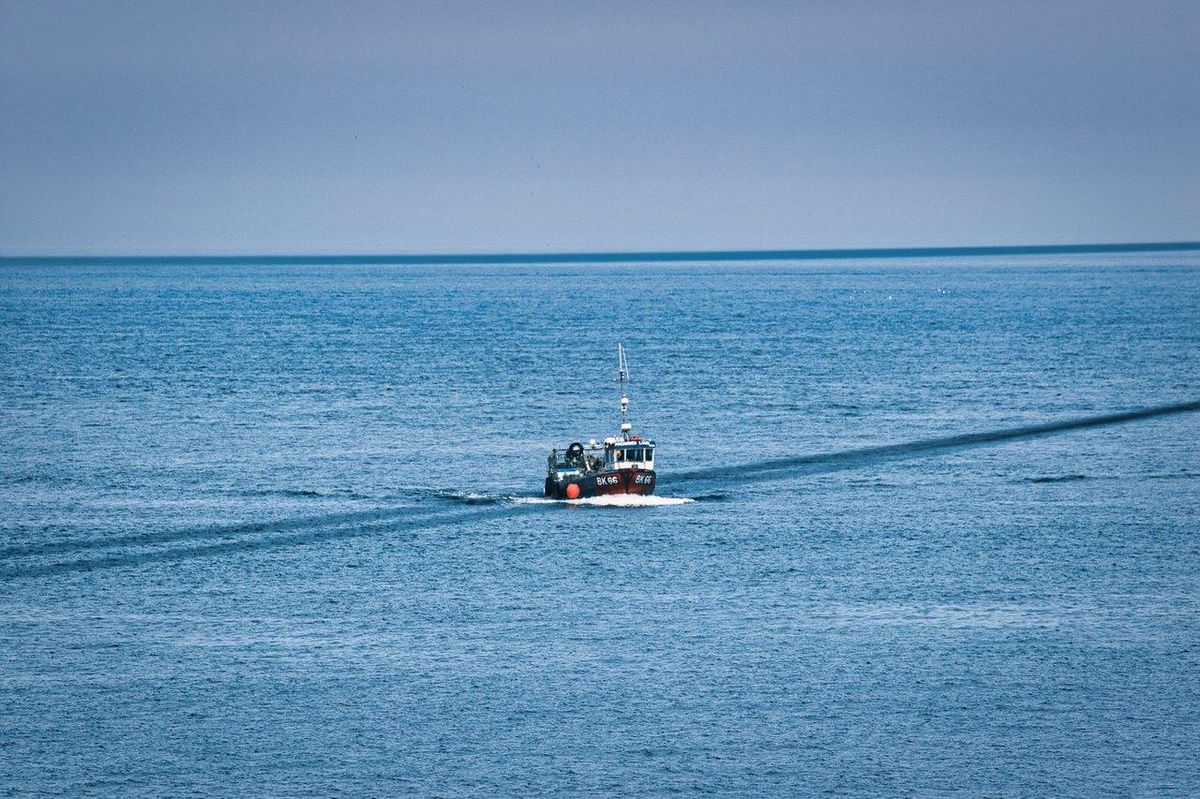 Groupe de pêcheurs en mer sur un bateau à fond bleu, parfait pour la summer sea fishing boat en été sur la côte française.