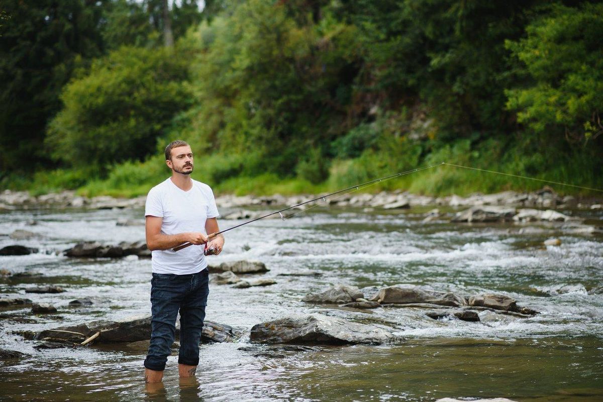 Jeune débutant en fly fishing effectuant un lancer précis sur une rivière irlandaise claire.