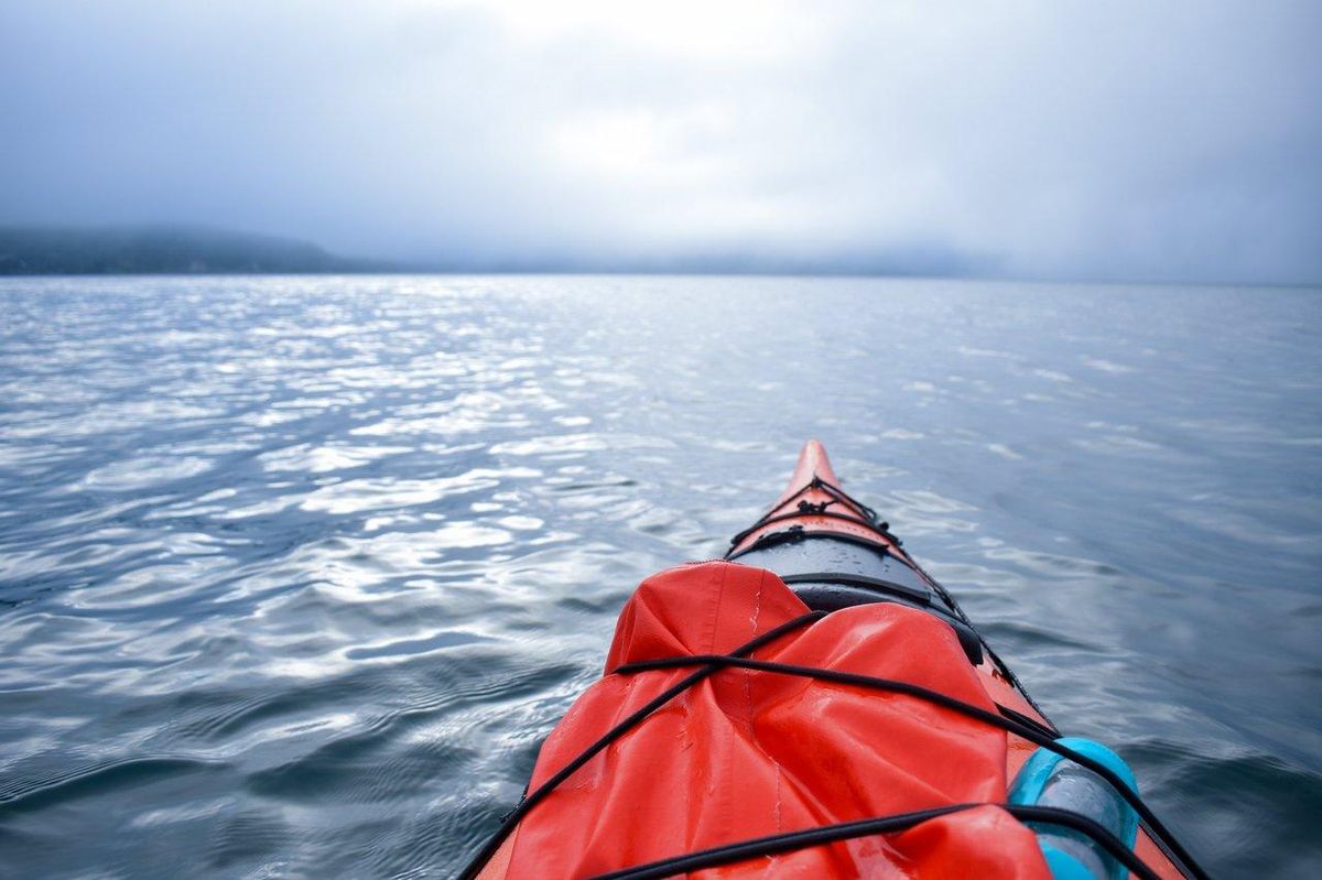 Kayakiste débutant en mer calme, portant un gilet de sauvetage, pratique la sécurité en kayak de mer.
