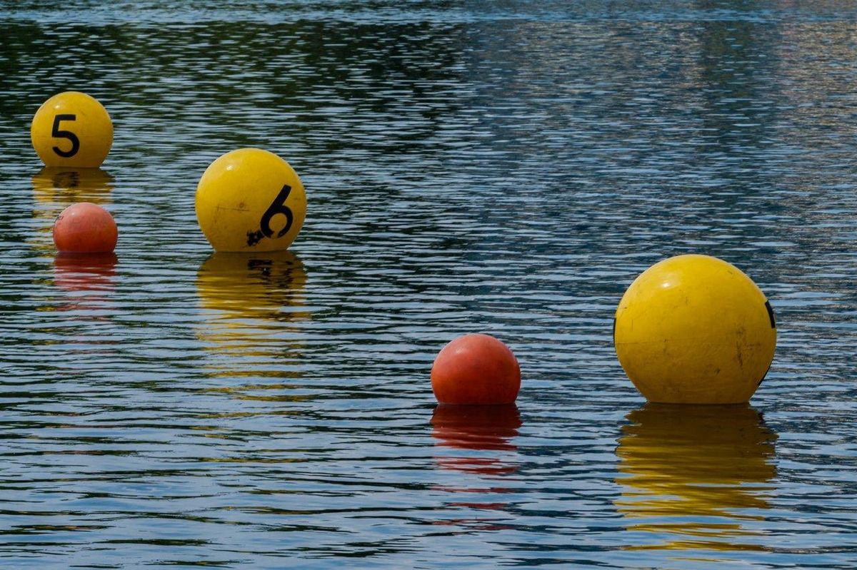 Nageur en mer avec un open water swimmer buoy coloré et bonnet, assurant sécurité et visibilité en eau libre.