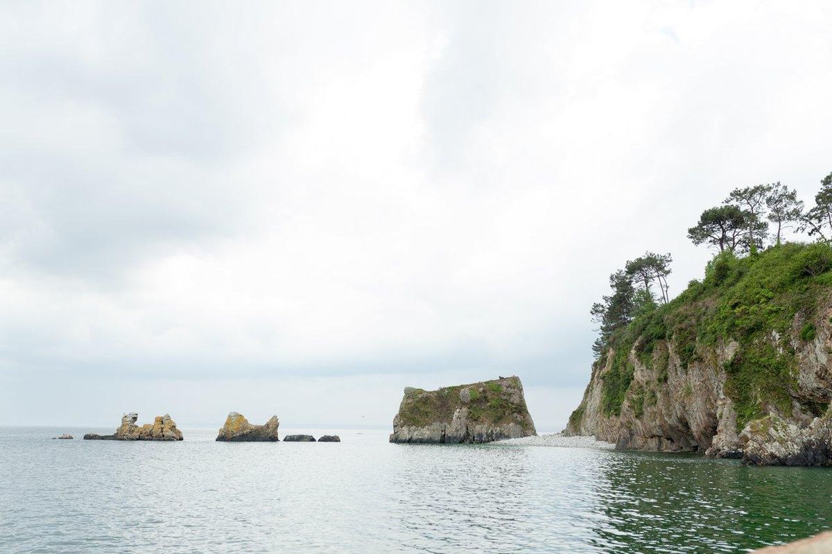 Sea kayak coastal landscape près de Morgat, côte rocheuse sous ciel clair en Bretagne, France.
