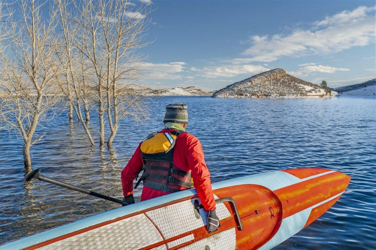 Sportif en paddleboarding sur un lac intérieur, équipé pour assurer sa sécurité en eaux calmes.