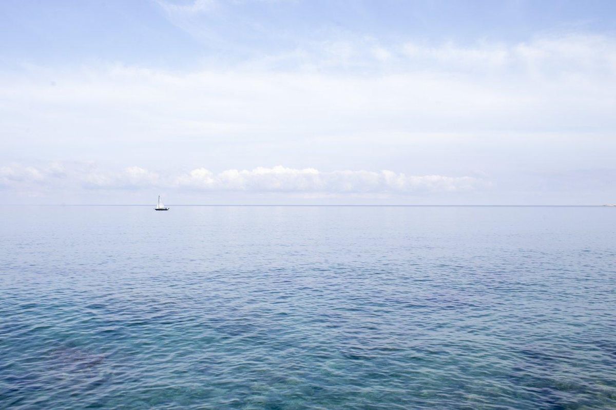 Un foilboard glisse en douceur sur une mer calme sous un ciel bleu dégagé, illustrant les tendances des sports nautiques 2026.