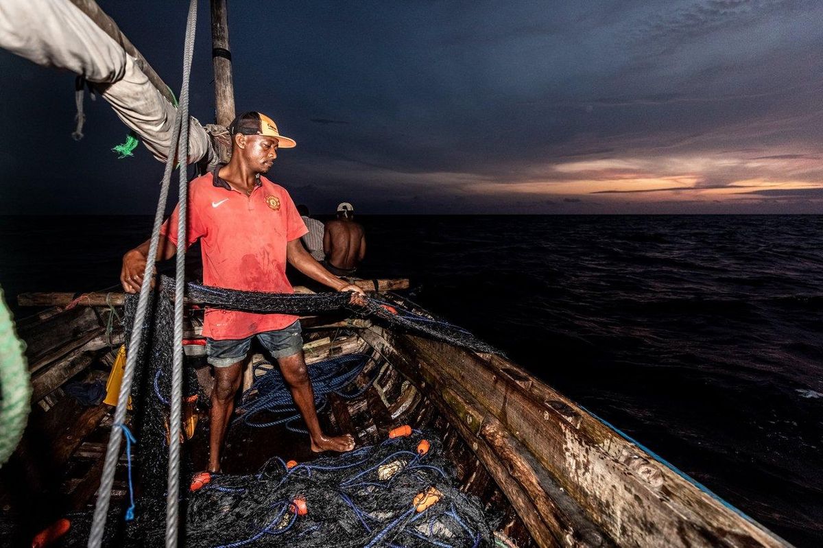 Un pêcheur nocturne préparant son matériel avec lampe frontale et canne équipée de bâtonnets lumineux pour la pêche sur le littoral.