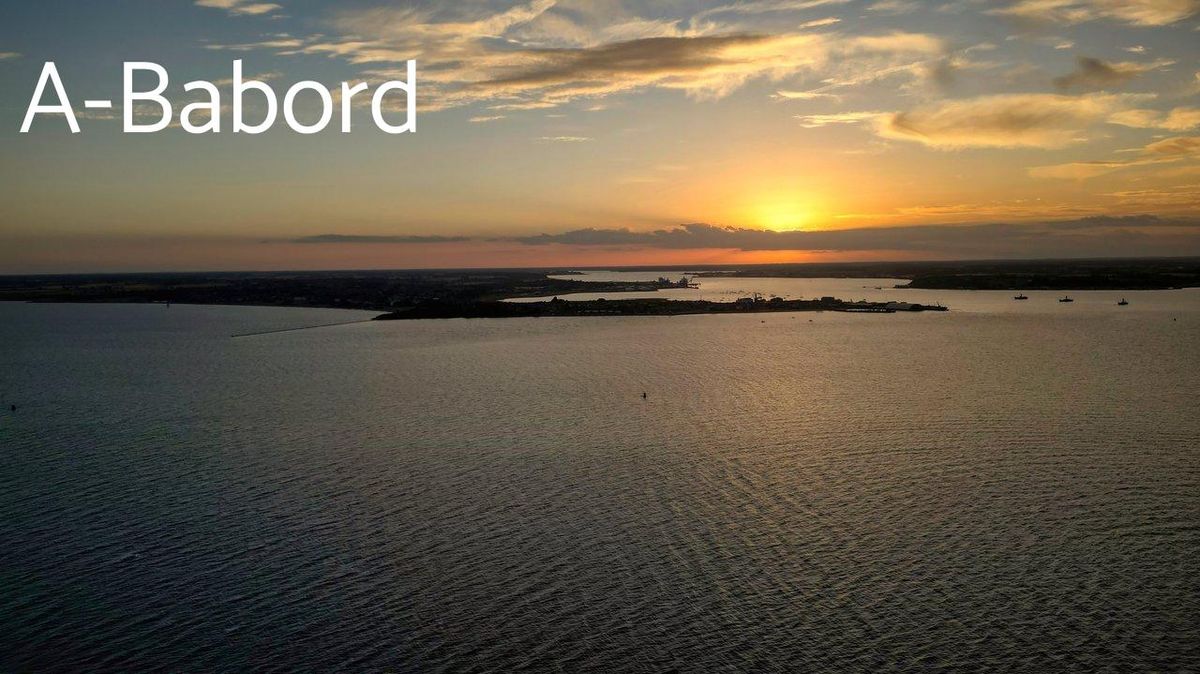 Un rider en wakeboard effectuant un backroll au coucher du soleil, capturé par drone sur un lac doré.