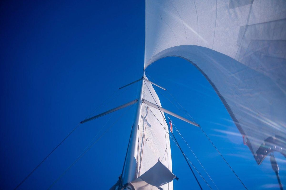Un solar sailing yacht moderne navigue en mer sous un ciel ensoleillé, illustrant l'innovation en sports nautiques 2025.
