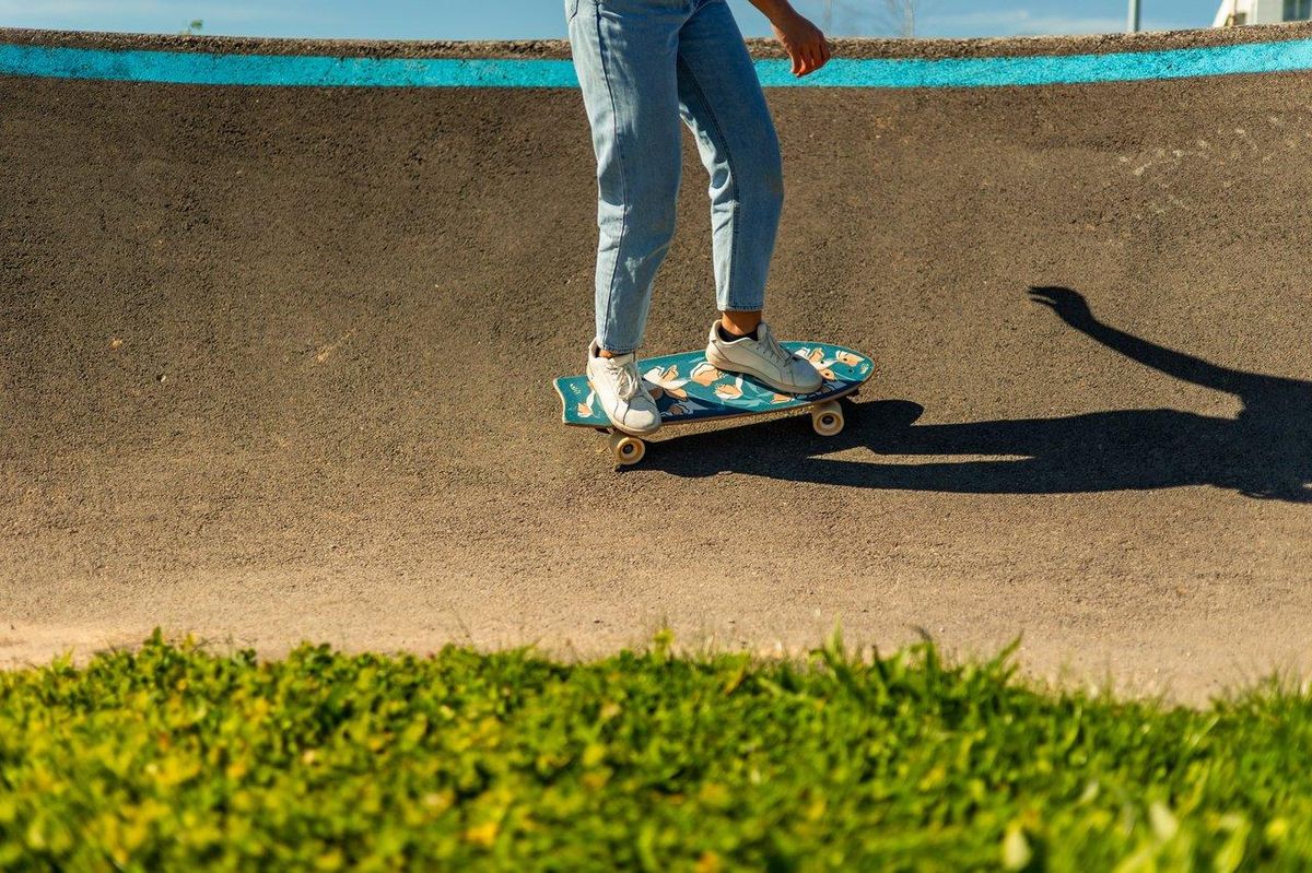 Un surfskate urban rider en pleine fluidité sur un pump track ensoleillé, illustrant l'amélioration de l’équilibre pour les sports nautiques.