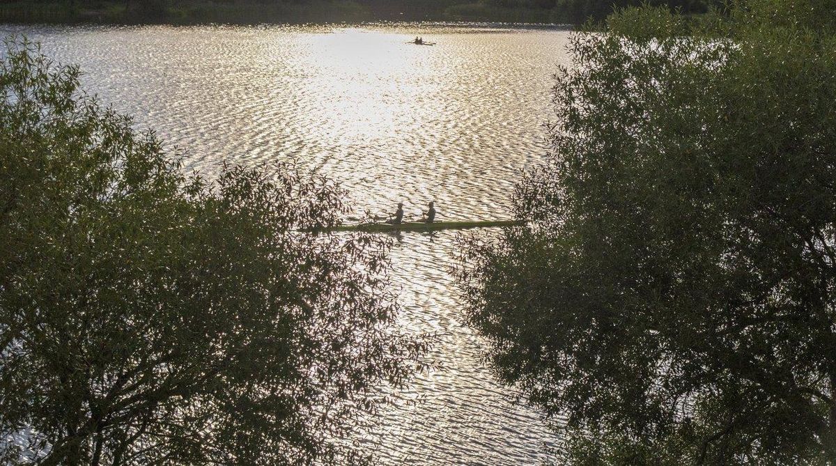 Une équipe de dragon boat en pleine compétition synchronisée sur un lac paisible, illustrant esprit d’équipe et coordination.