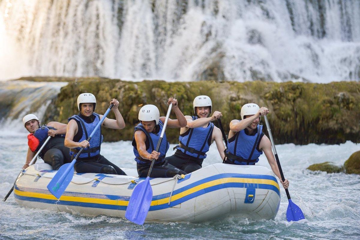 Une équipe de whitewater rafting en pleine descente sur une rivière alpine, symbole d’aventure et de sport en groupe.