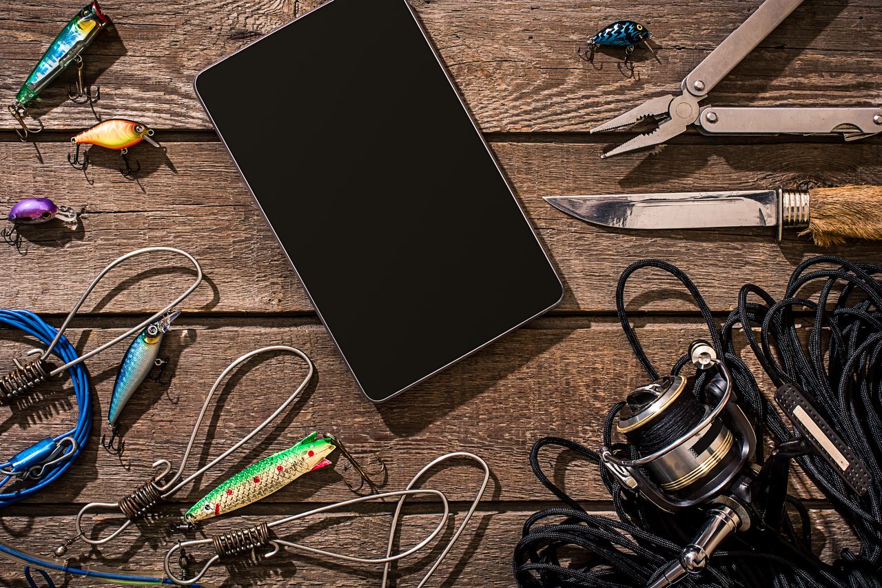 Application RecFishing sur smartphone avec carnet de pêche et accessoires de matériel, vue du dessus.
