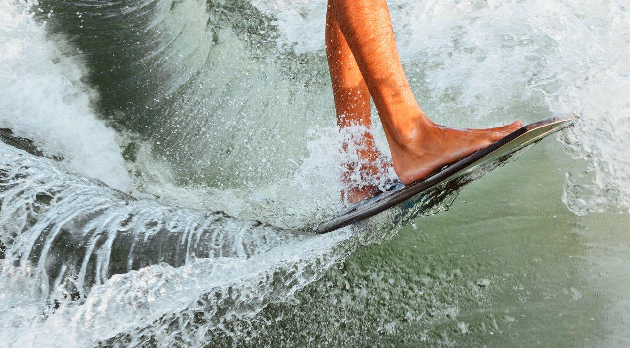 Entraînement débutant en indoor wakesurf, avec système de traction par câble sur un wakepark intérieur.