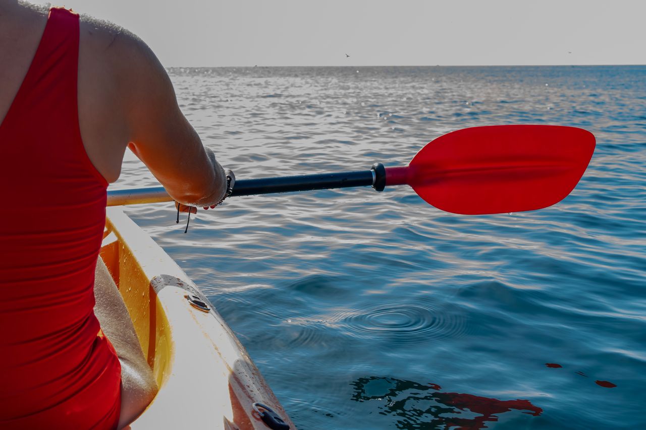 Kayak de pêche à pédales sur plan d’eau calme, équipé de cannes et sondeur.