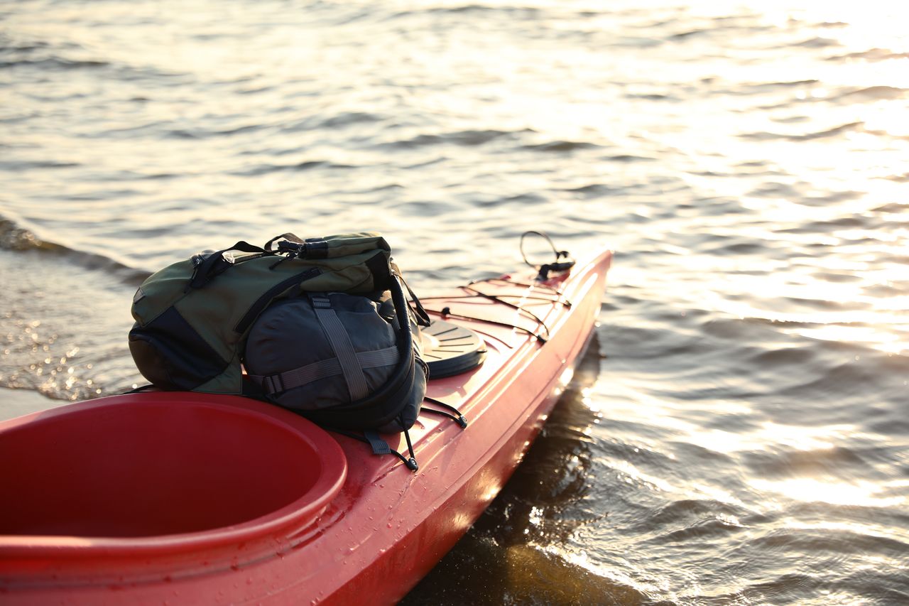 Kayak pliable rouge avec sac de transport sur un quai, idéal pour le voyage et l’aventure
