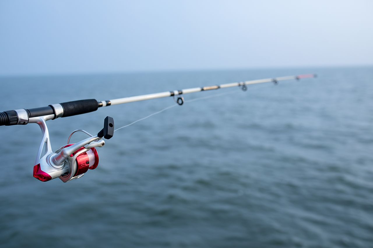 Moulinet de pêche électrique monté sur une canne, sur le pont d’un bateau en mer.