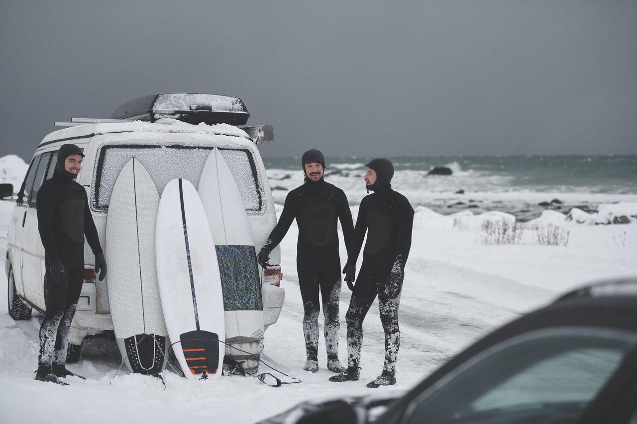 Surfers en wetsuits hiver 5/4mm sur une plage rocheuse en Norvège après une session hivernale.