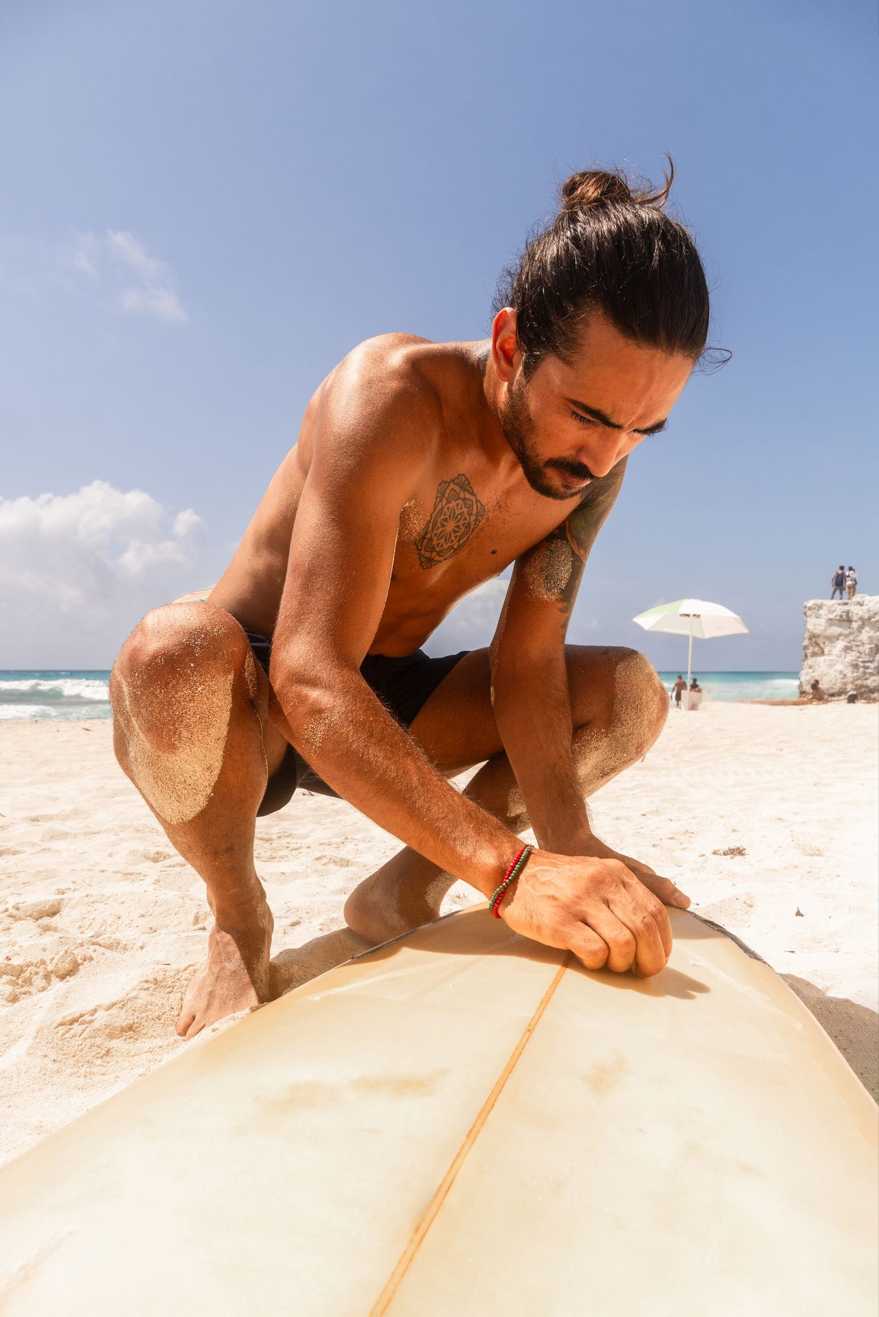 Surfeur débutant préparant sa planche en mousse sur une plage ensoleillée avant la session de surf.