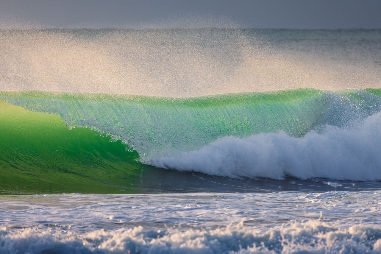 Surfeur en action dans une vague creuse au coucher du soleil, ambiance de compétition mondiale.