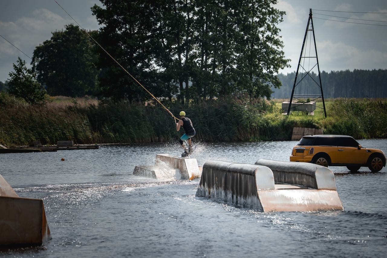 Wakeboarder en action sur un module de câble, équilibre et technique dans un parc nautique européen.