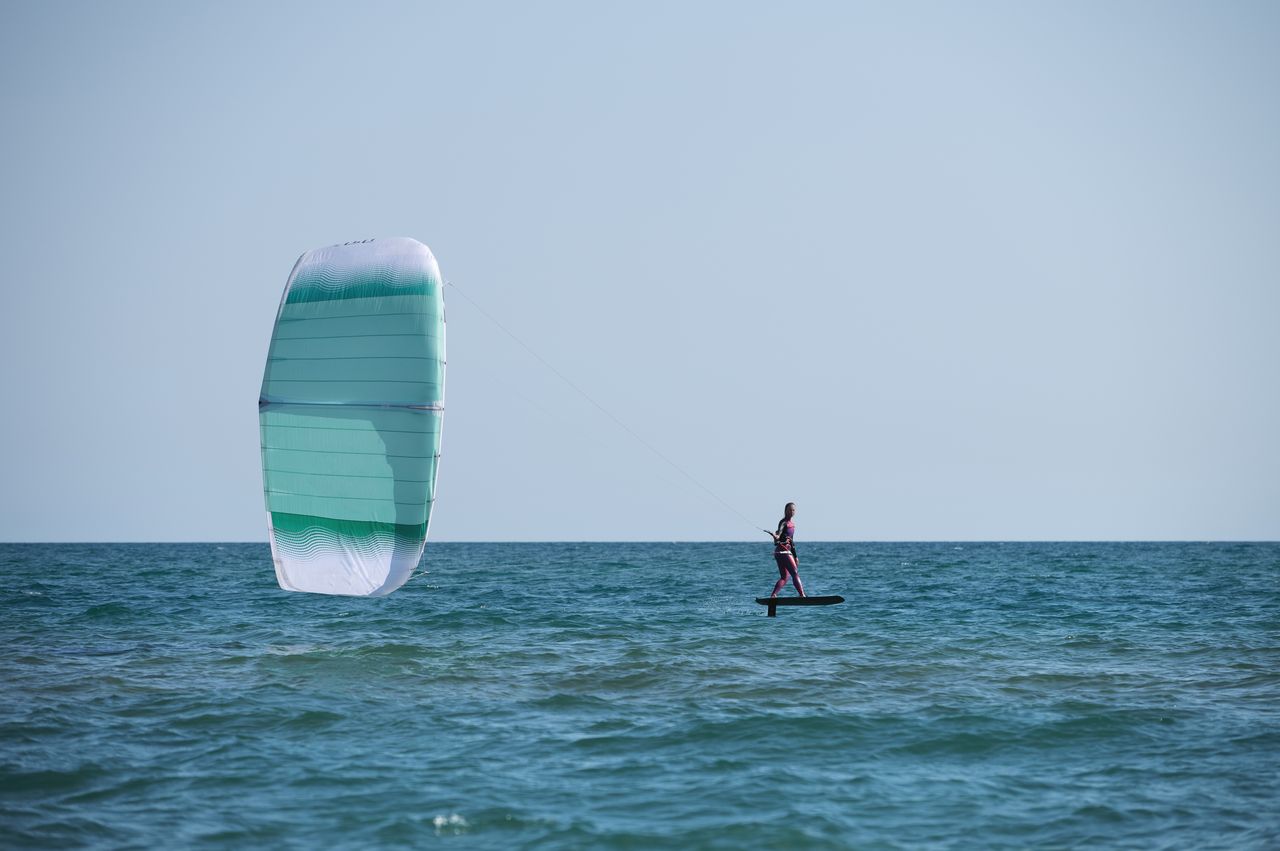 Wingfoiler glissant sur une mer Méditerranée calme, porté par le vent d’été en hydrofoil.