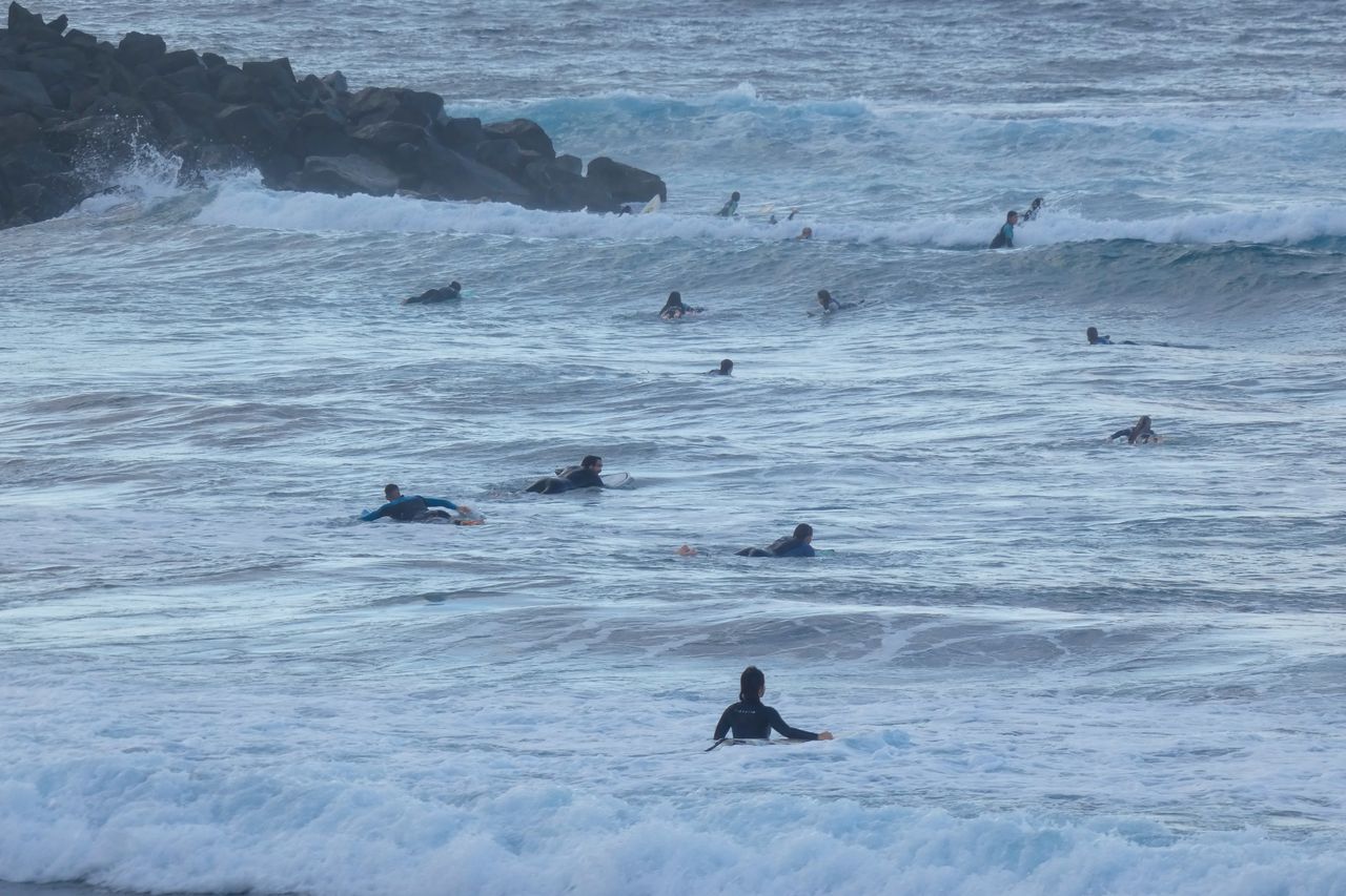École de surf sur plage hivernale, débutants apprenant sur de douces vagues océaniques.
